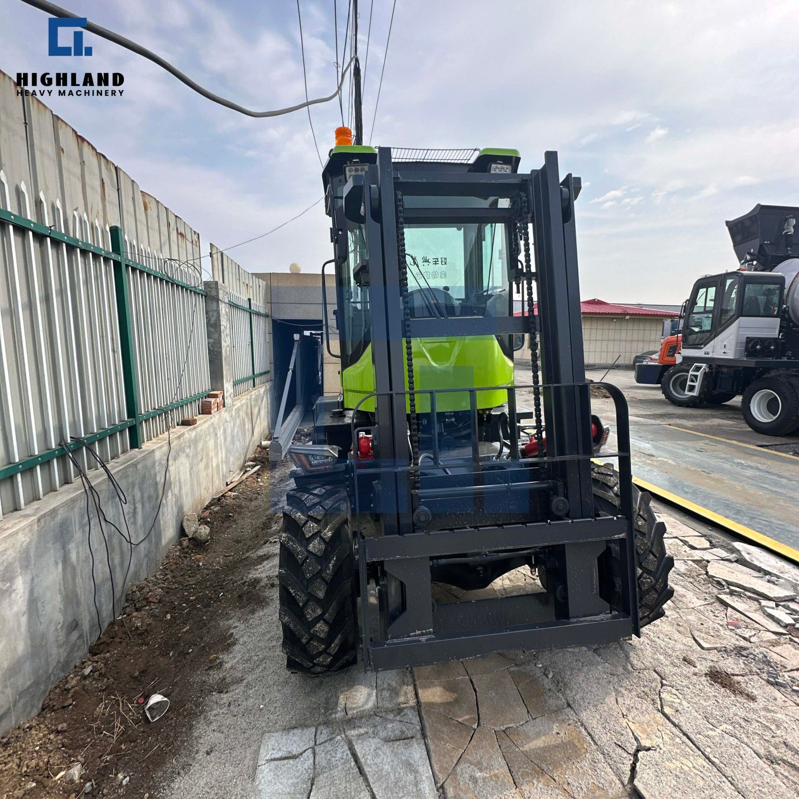 HIGHLAND HEAVY MACHINERY 3.5-ton front articulated rough terrain forklift with a heavy-duty black mast, enclosed green cabin, and orange safety warning light, parked in an industrial yard.