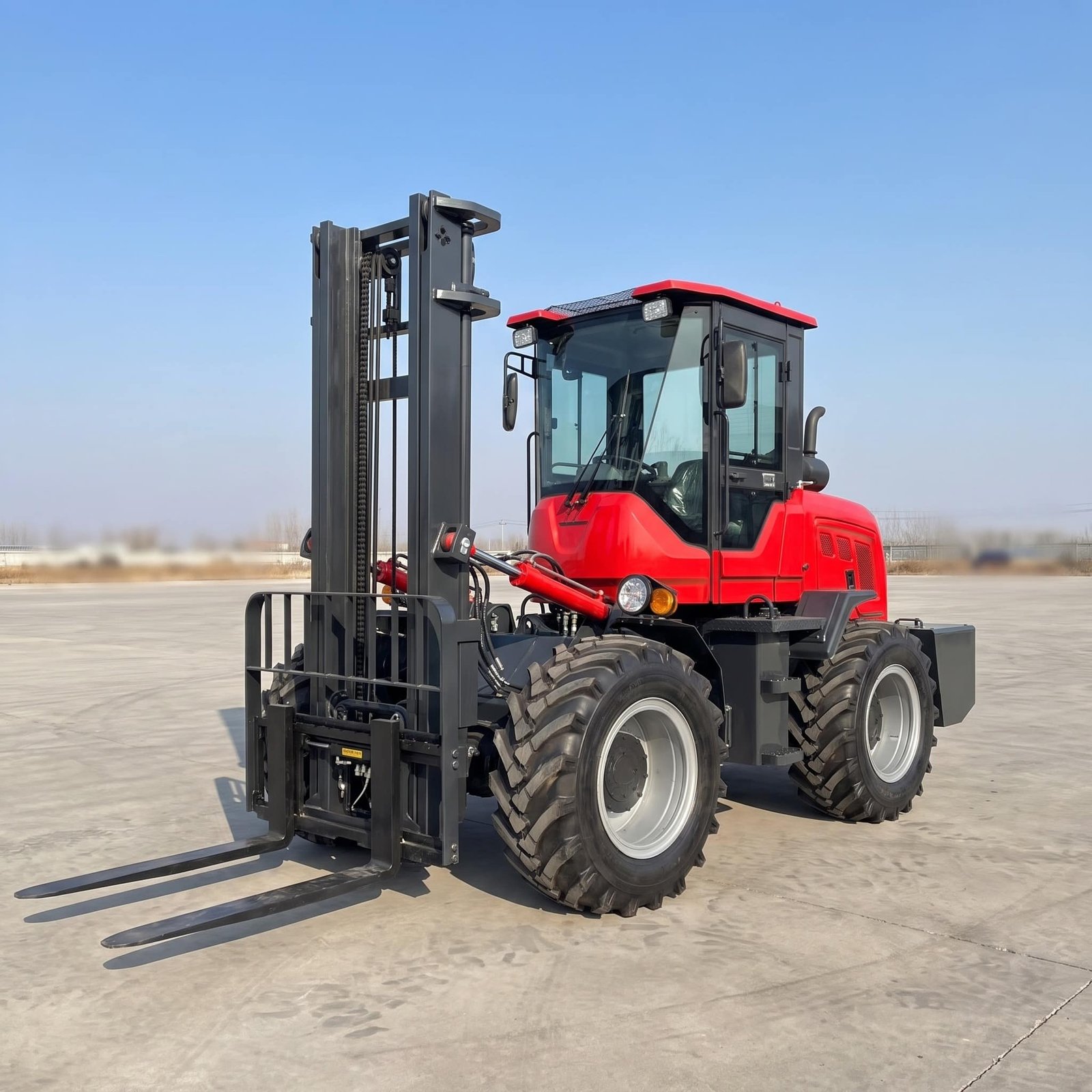 HIGHLAND HEAVY MACHINERY red rough terrain forklift parked alone on a concrete pad under a clear blue sky, standing ready for field service and maintenance support.