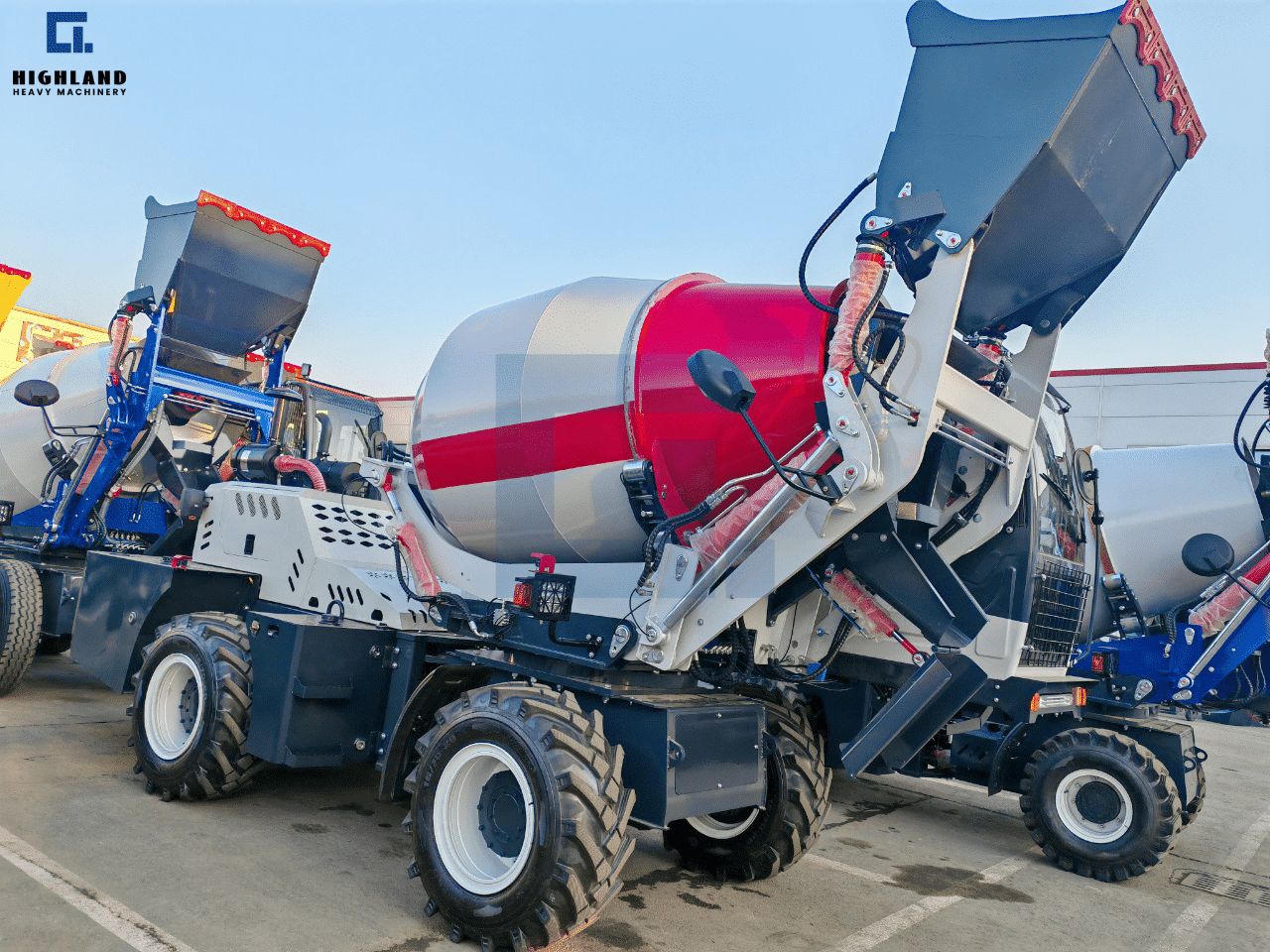 HIGHLAND HEAVY MACHINERY 2.6m³ red and white self loading concrete mixer truck with a raised high-tip bucket, parked in a factory yard, showcasing key operational parameters for buyer evaluation.