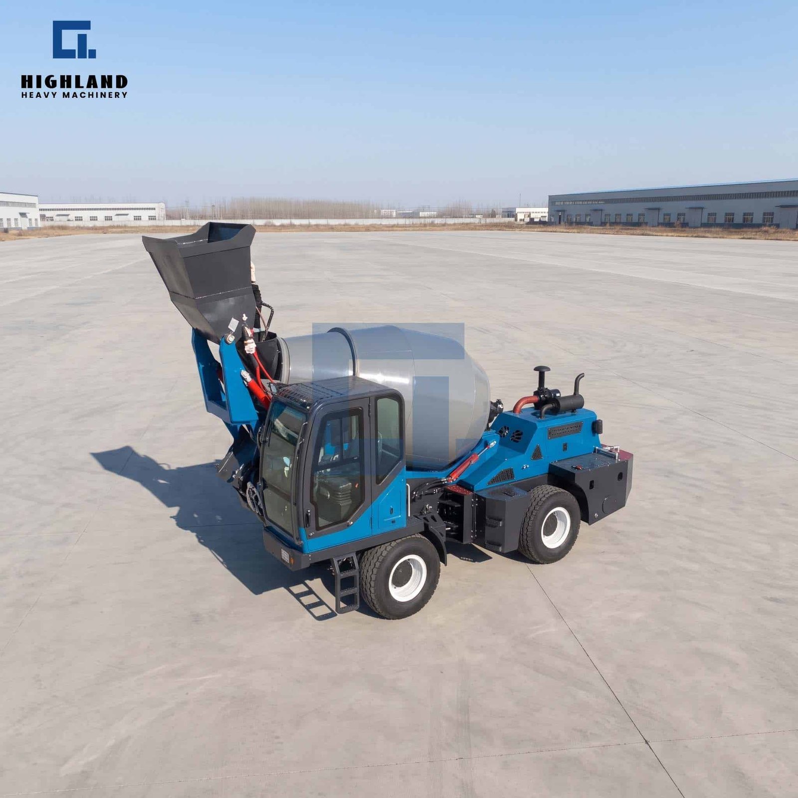 HIGHLAND HEAVY MACHINERY blue self loading concrete mixer truck with a raised high-tip bucket, parked on a vast open concrete site under a clear sky, designed for maximum operational efficiency on large-scale construction projects.