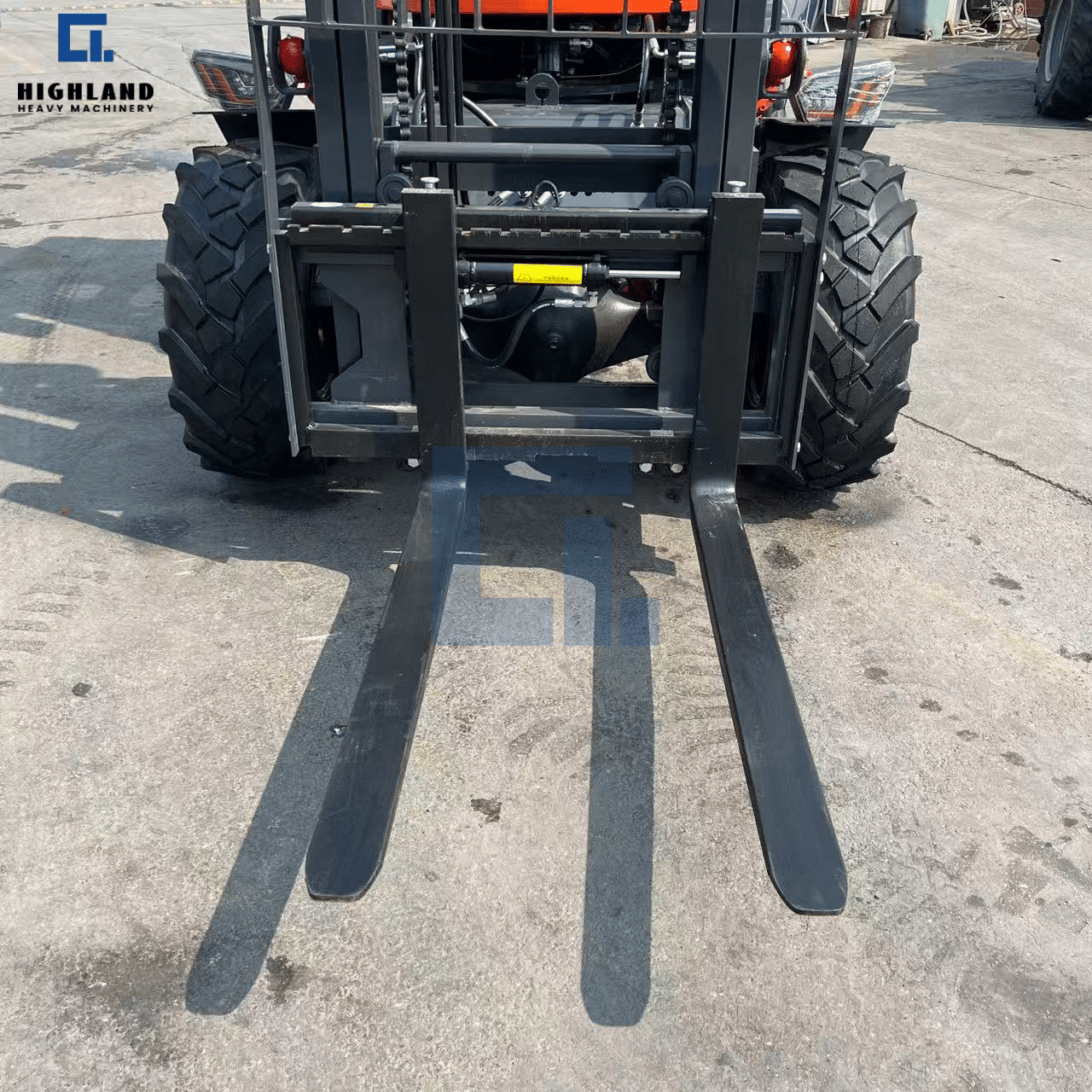 HIGHLAND HEAVY MACHINERY off-road forklift heavy-duty steel forks and mast close-up, showing the robust lifting mechanism and industrial tires on a construction yard.