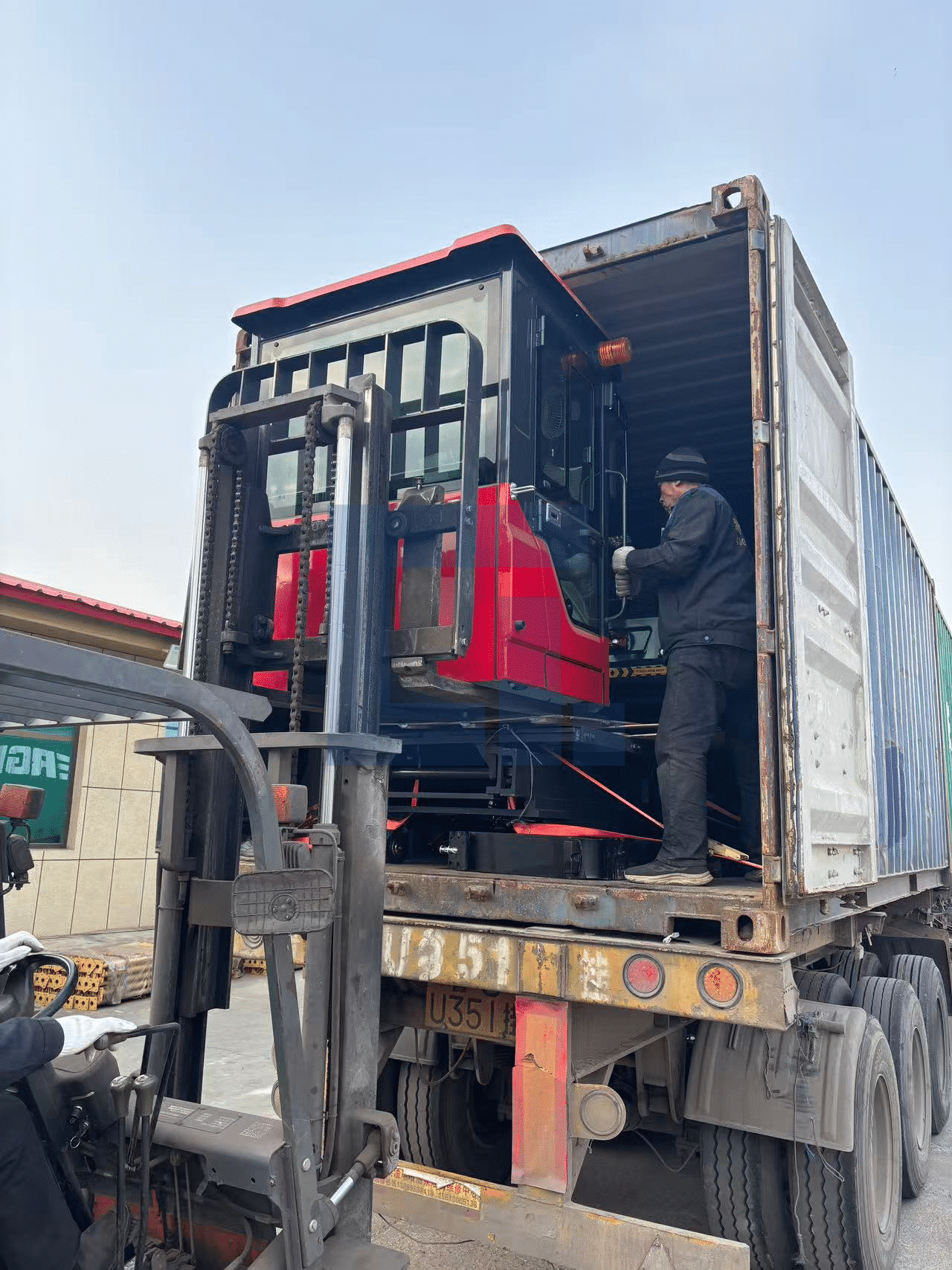 HIGHLAND HEAVY MACHINERY red rough terrain forklift being carefully loaded into a shipping container, demonstrating secure export packing and reliable global logistics for heavy equipment.
