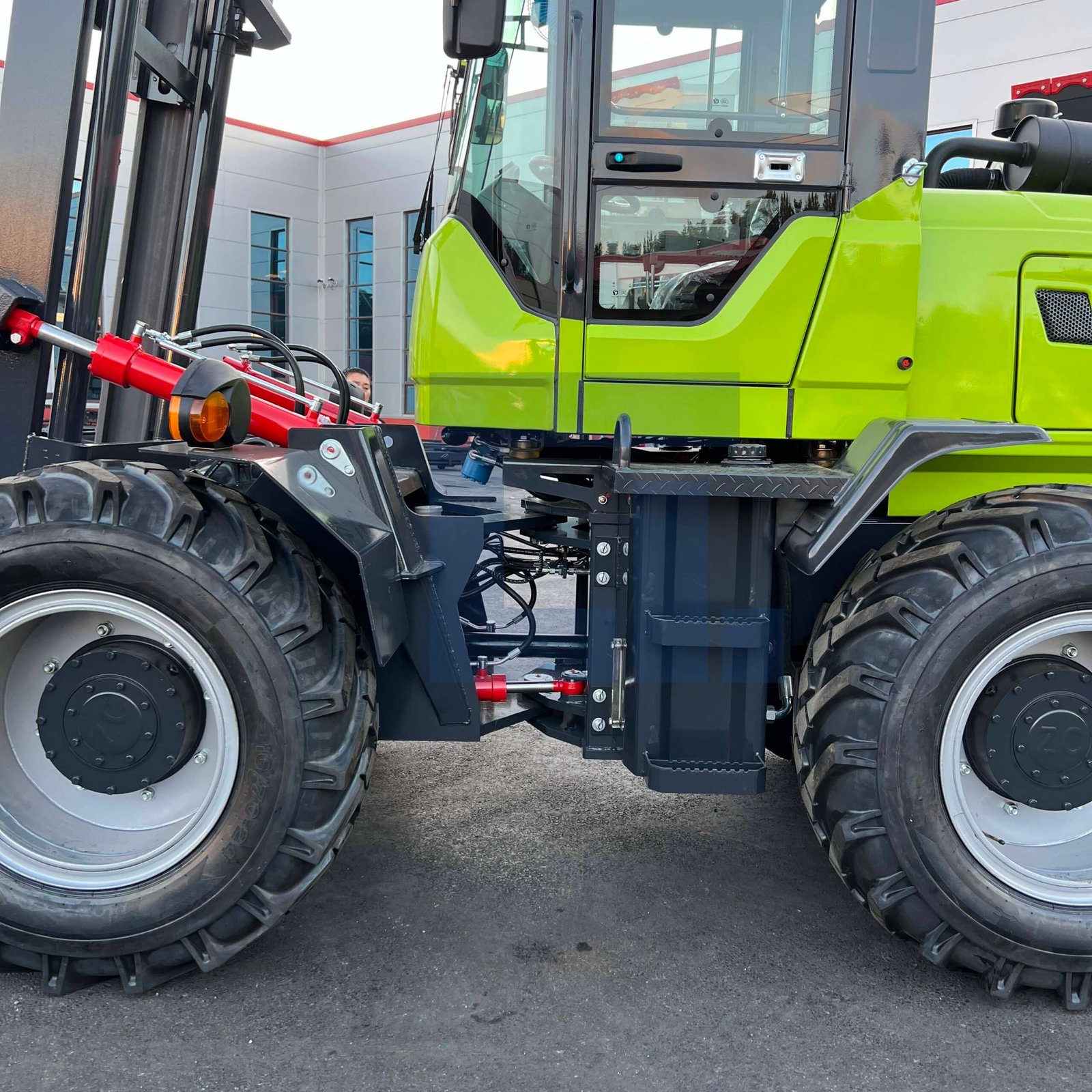 HIGHLAND HEAVY MACHINERY rough terrain forklift chassis close-up, featuring massive off-road tires and heavy-duty steering cylinders for extreme durability and reduced maintenance costs.