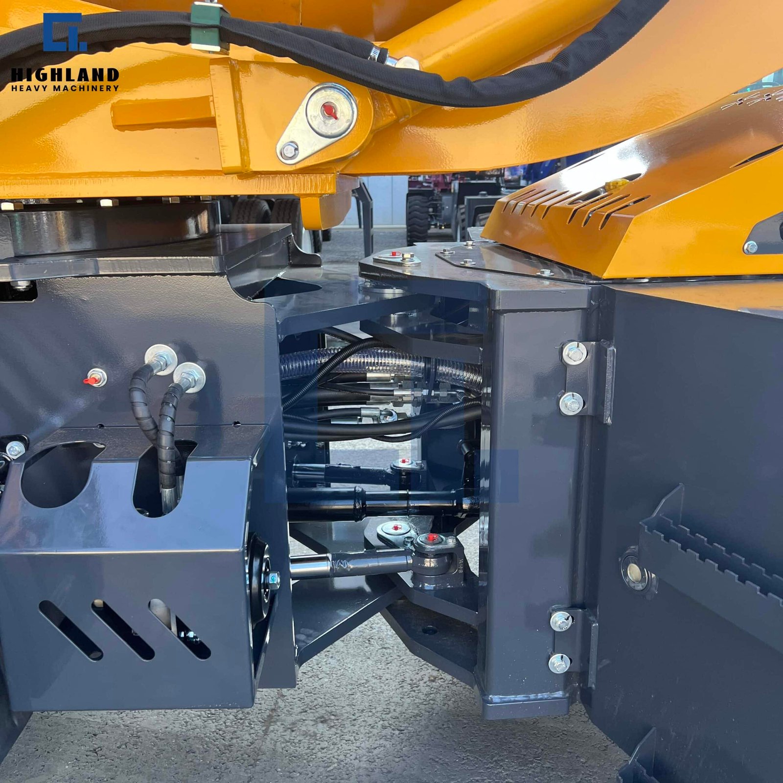 HIGHLAND HEAVY MACHINERY self loading concrete mixer truck articulated chassis and steering joint close-up, highlighting the heavy-duty steel structure, protection plates, and precise hydraulic line routing for superior maneuverability.